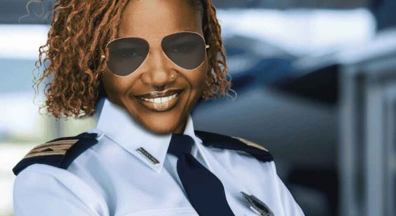 A smiling woman wearing a pilot uniform and aviator sunglasses stands confidently with arms crossed in front of an airplane.