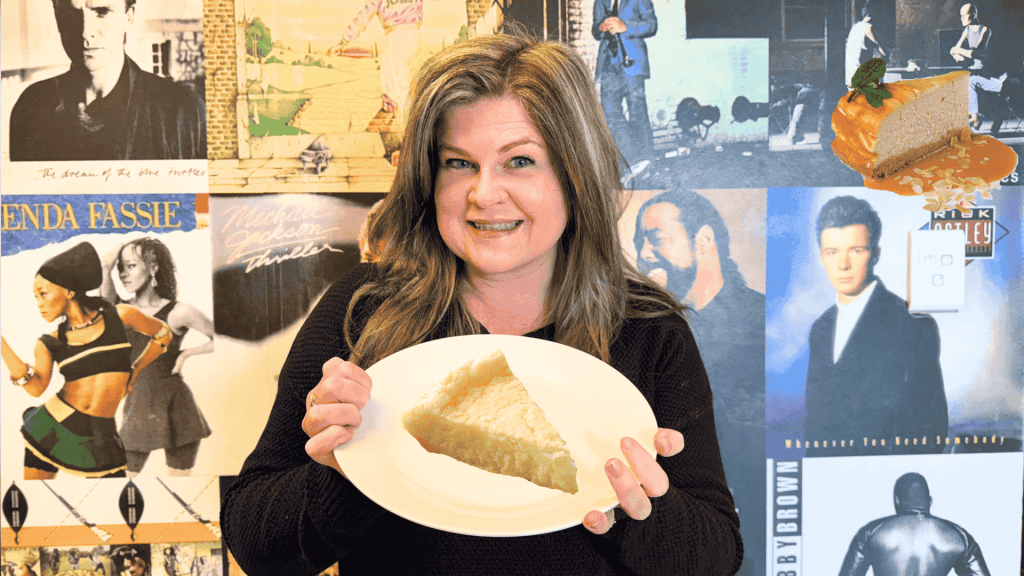 A woman smiles while holding a plate with a slice of pie in front of a wall covered with vintage music album covers. A floating cheesecake slice with caramel sauce and mint is visible in the top right corner.