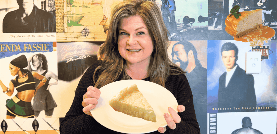A woman smiles while holding a plate with a slice of pie in front of a wall covered with vintage music album covers. A floating cheesecake slice with caramel sauce and mint is visible in the top right corner.