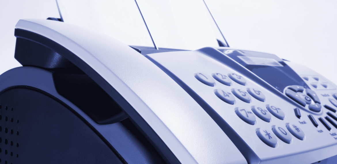 Close-up of a fax machine with paper inserted, showing its keypad and control panel. The image has a blue tint and focuses on the device’s buttons and curved edges.