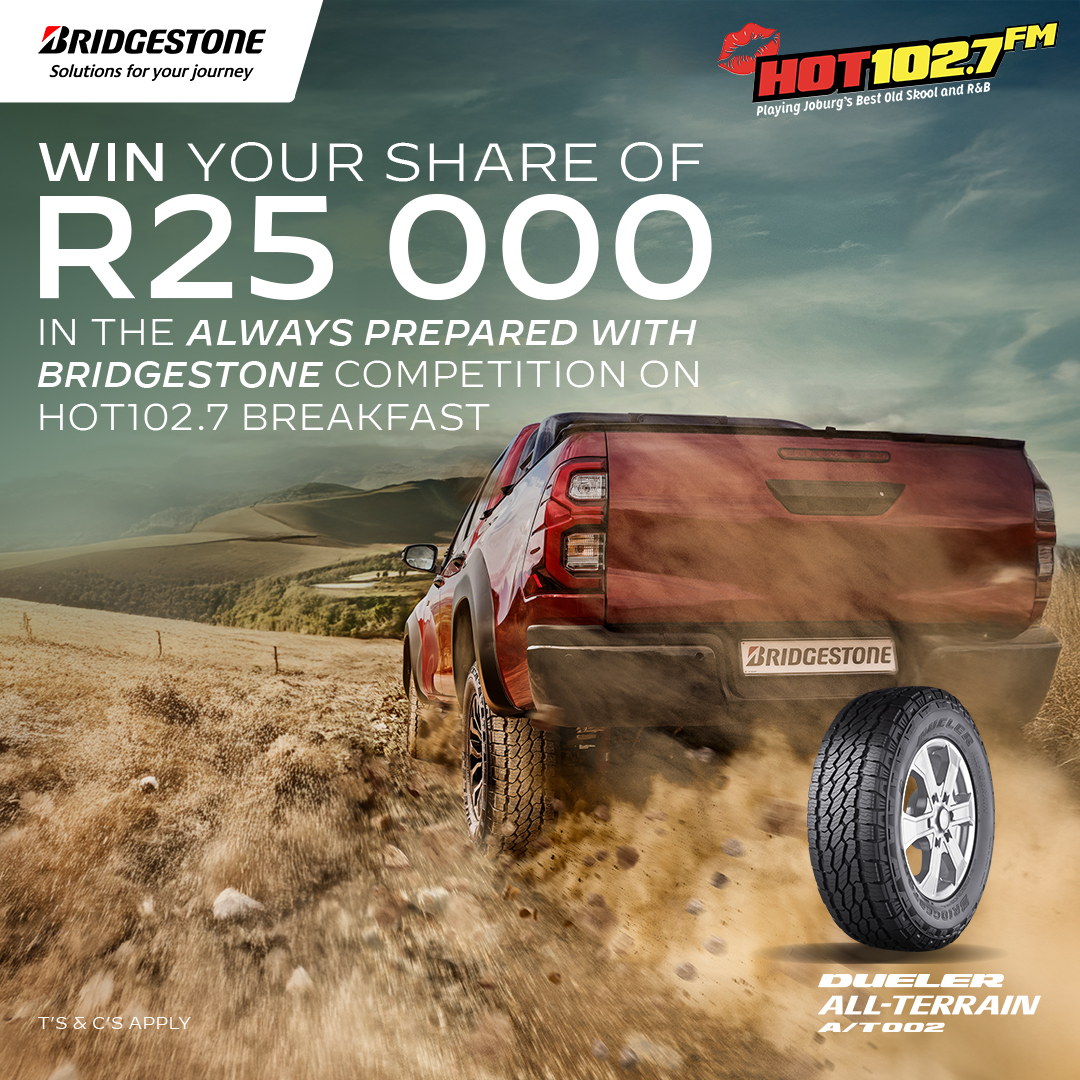 A red pickup truck drives through muddy terrain with a Bridgestone Dueler All-Terrain A/T002 tire in the foreground. Celebrate Heritage Day and win a share of R25,000 in a Bridgestone and HOT 102.7 FM competition.