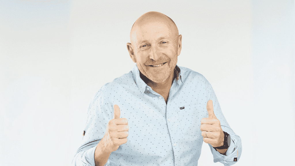 A smiling bald man wearing a light blue button-up shirt gives two thumbs up against a plain light background, showing he's clearly free from any brainrot.