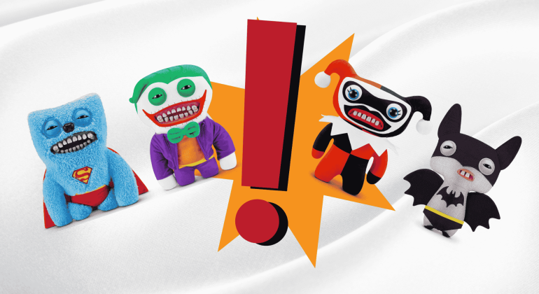Four plush toys styled as comic book characters—Superman, Joker, Harley Quinn, and Batman—with wide grins stand around a large red exclamation mark on a white wavy background, bringing a playful twist to homeownership décor.