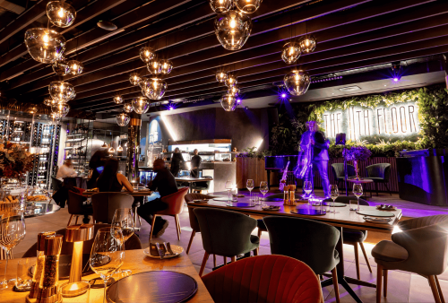 A stylish restaurant with modern lighting, elegant table settings, and a neon sign reading THE 17th FLOOR on the wall. On heritage day, guests are seated and staff move about, creating a lively, upscale atmosphere.