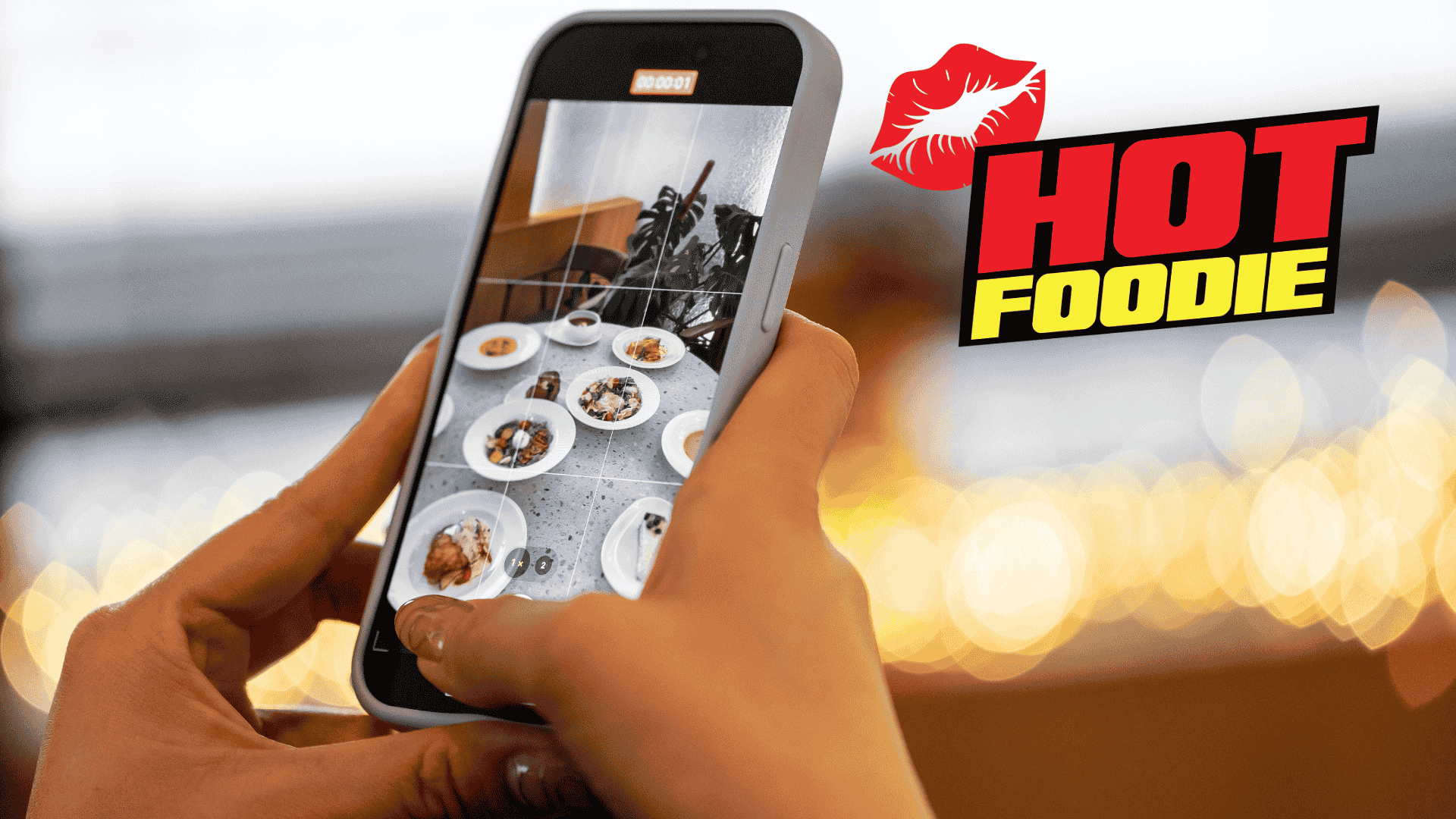 A person takes a photo of various plated dishes with a smartphone. The background is blurred lights, and the words HOT FOODIE with a red lips graphic appear on the right side, celebrating heritage day flavors.