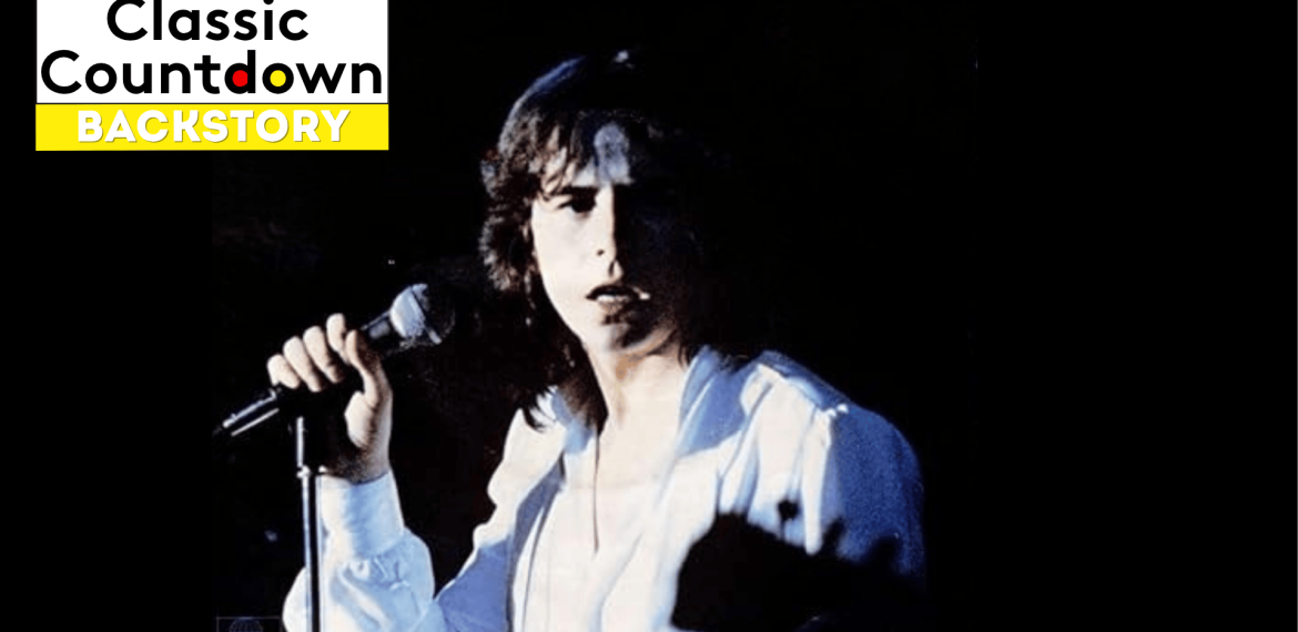 A young man with long hair wearing a white shirt holds a microphone and sings on stage against a dark, blurred background. The Classic Countdown Backstory logo appears in the top left corner of the image.