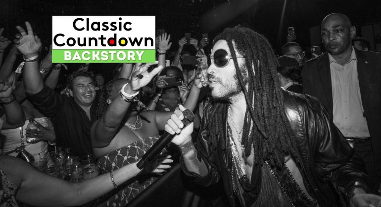 Black and white photo of a singer with dreadlocks and sunglasses performing closely to an excited crowd, capturing the energy as "Love is in the Air" plays; Classic Countdown Backstory text appears in the top left corner.