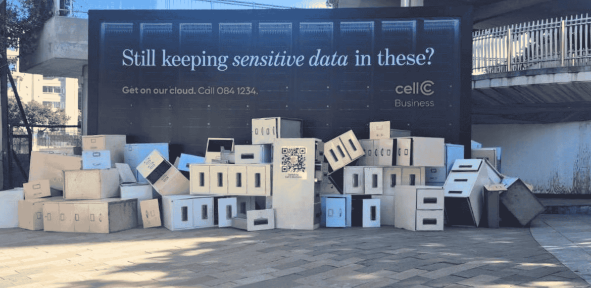 A large billboard reads Still keeping sensitive data in these? above a pile of white and beige cardboard storage boxes, promoting cellC Business cloud services—perfect for storing everything from matric records to critical business files.