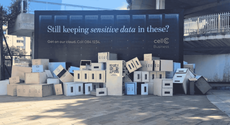 A large billboard reads Still keeping sensitive data in these? above a pile of white and beige cardboard storage boxes, promoting cellC Business cloud services—perfect for storing everything from matric records to critical business files.