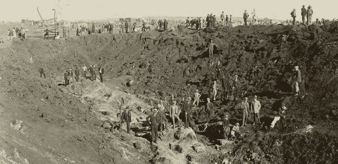 Historical photo of many people working in a large, deep excavation site—much like the vibrant eras Miriam Makeba witnessed—shows dirt mounds and workers scattered throughout the scene.