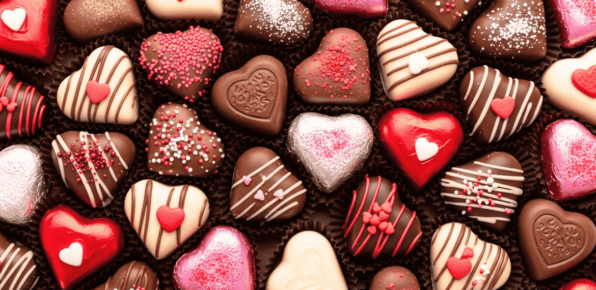 Assorted heart-shaped chocolates in various colors and decorations, perfect for celebrating a matric milestone. Pink, red, white, and brown treats with sprinkles, stripes, and small heart candies are arranged closely together.