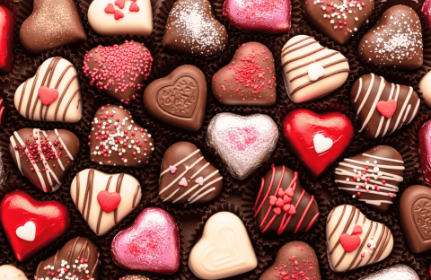Assorted heart-shaped chocolates in various colors and decorations, perfect for celebrating a matric milestone. Pink, red, white, and brown treats with sprinkles, stripes, and small heart candies are arranged closely together.