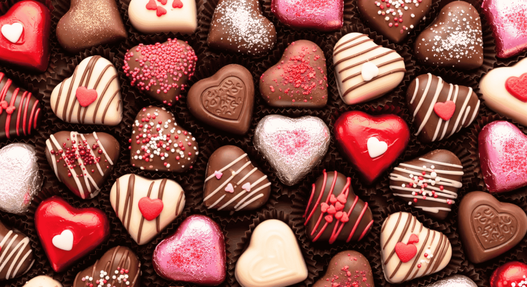 Assorted heart-shaped chocolates in various colors and decorations, perfect for celebrating a matric milestone. Pink, red, white, and brown treats with sprinkles, stripes, and small heart candies are arranged closely together.