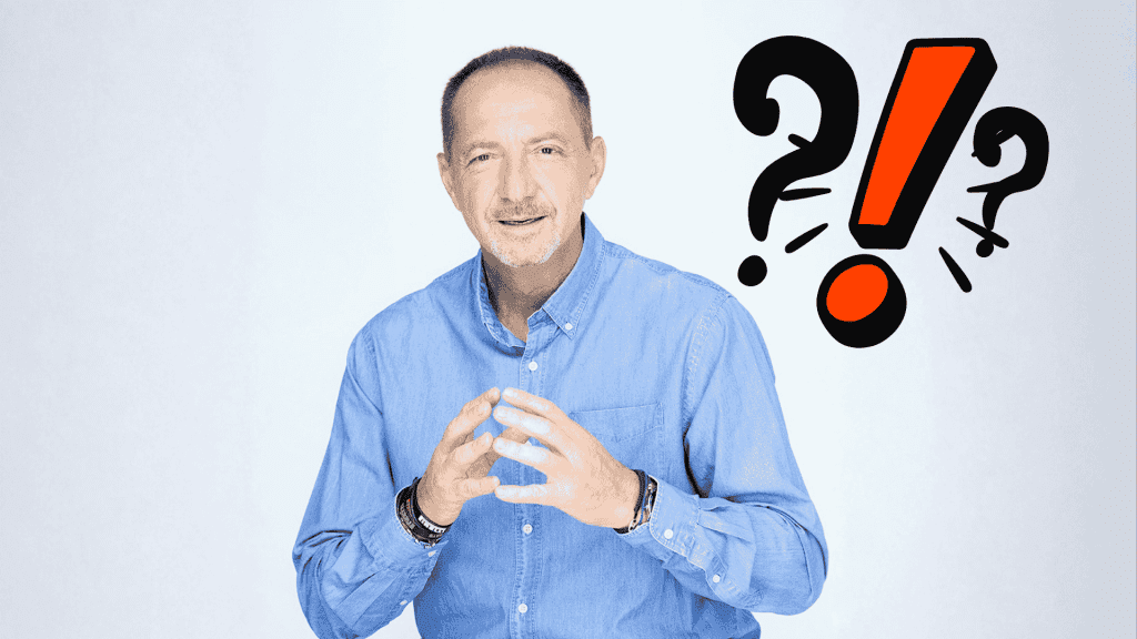 A man in a blue shirt gestures with his hands and smiles at the camera. Behind him are bold question marks and an exclamation mark, suggesting travel confusion or surprise. The background is light and plain.