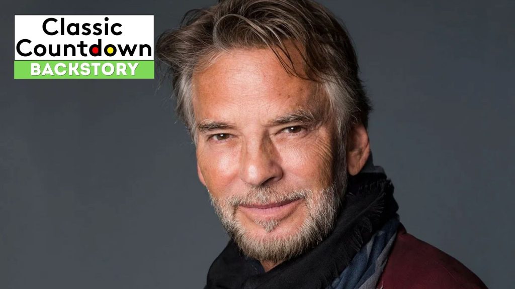 A man with gray hair and a trimmed beard smiles softly at the camera, wearing a dark scarf and jacket. "Classic Countdown Backstory" and "Last Christmas" are displayed in the top left corner on a black, white, and green background.
