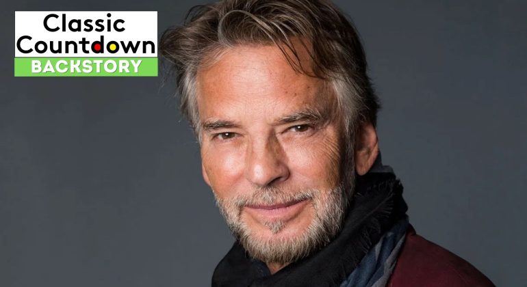 A man with gray hair and a trimmed beard smiles softly at the camera, wearing a dark scarf and jacket. "Classic Countdown Backstory" and "Last Christmas" are displayed in the top left corner on a black, white, and green background.