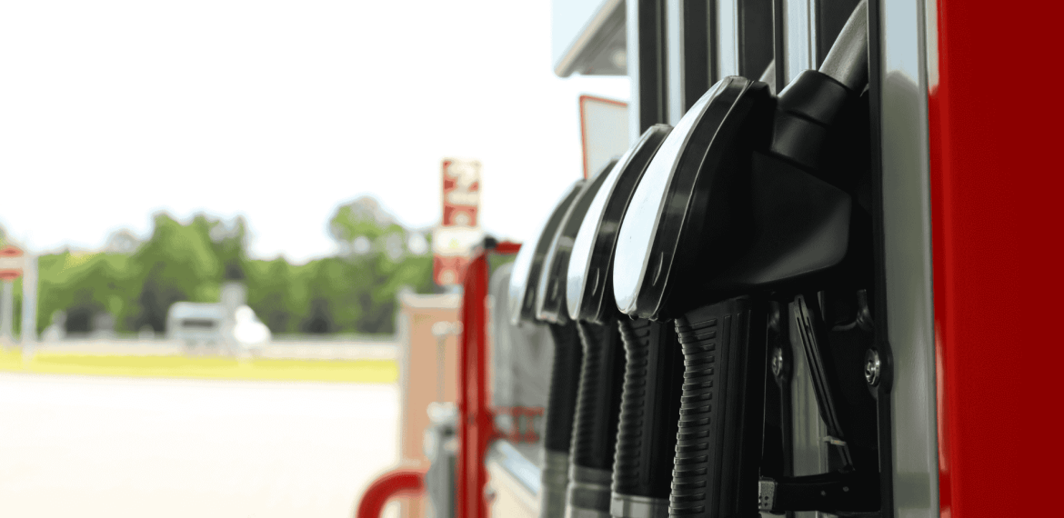 Close-up view of several black fuel pump handles at a gas station, with a blurred background showing trees and an empty forecourt—a striking scene reminiscent of a new show lineup waiting to debut.