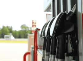 Close-up view of several black fuel pump handles at a gas station, with a blurred background showing trees and an empty forecourt—a striking scene reminiscent of a new show lineup waiting to debut.
