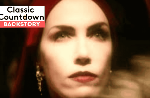 A close-up of a woman with red lipstick and a red headscarf, wearing drop earrings. The image is softly focused. Overlay text reads “Classic Countdown Backstory” in bold white and black letters on a red and white background.