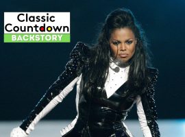 A woman in a black and white stage outfit performs with an intense expression, channeling Cher’s iconic presence. Behind her is a Classic Countdown Backstory graphic with black, white, and green text against a dark, blurred background.