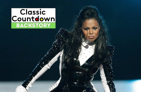 A woman in a black and white stage outfit performs with an intense expression, channeling Cher’s iconic presence. Behind her is a Classic Countdown Backstory graphic with black, white, and green text against a dark, blurred background.