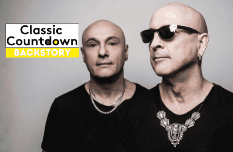 Two bald men in black shirts and silver jewelry stand side by side; one wears sunglasses. Against a gray background, a Classic Countdown Backstory logo appears in the upper left, recalling the cool style of Robert Palmer.