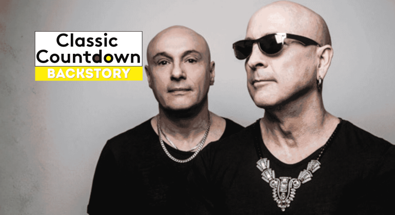 Two bald men in black shirts and silver jewelry stand side by side; one wears sunglasses. Against a gray background, a Classic Countdown Backstory logo appears in the upper left, recalling the cool style of Robert Palmer.