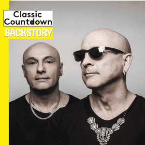 Two bald men wearing black shirts and necklaces pose together against a gray background. One man, channeling Robert Palmer’s iconic style with dark sunglasses, stands beneath text that reads Classic Countdown Backstory in the top left corner.