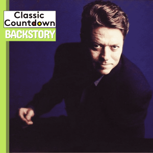 A person with light brown hair in a dark suit looks up towards the camera against a dark blue background. The top left corner has the text Classic Countdown Backstory in bold, stylized letters.