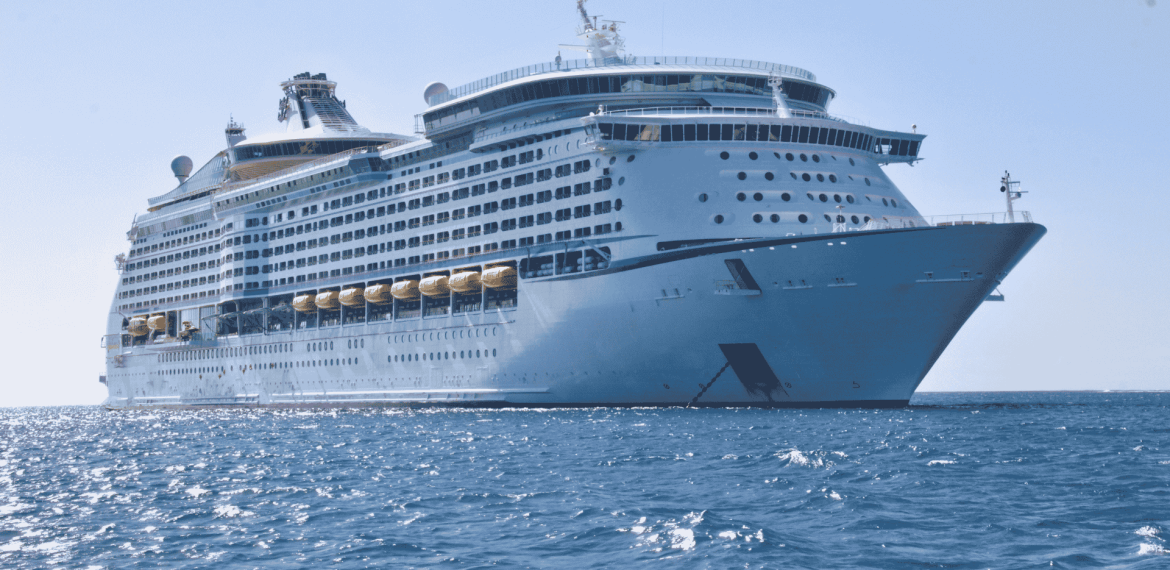A large white cruise ship, reminiscent of the grandeur seen in Lloyd Madurai’s fleet, floats on calm blue ocean water under a clear sky, viewed from a low angle near the front of the vessel.