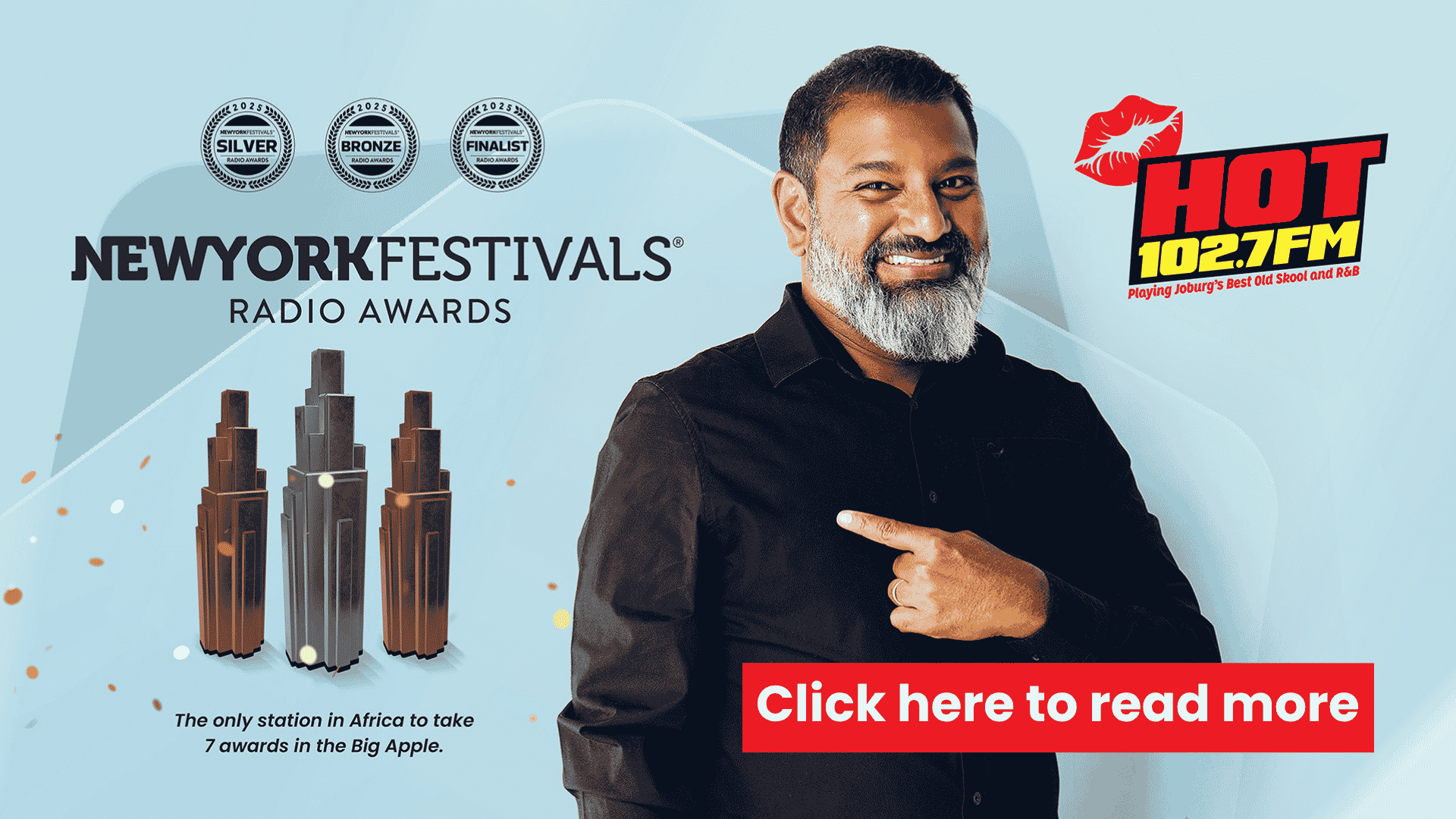 A smiling man with a beard points to the right. Beside him are awards and the text New York Festivals Radio Awards. The HOT 102.7FM logo and a red button read Click here to read more.