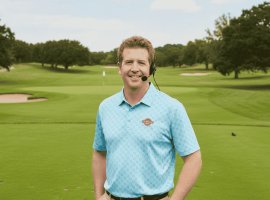 A man in a blue polo shirt and headset stands smiling on a green golf course, with trees, sand traps, and a golf flag visible in the background. A Hot 1027 Breakfast sign is seen on the right side of the image.