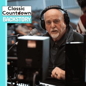 An older man wearing headphones speaks into a microphone in a recording studio. Text on the image reads: Classic Countdown BACKSTORY, diving into legends like Robert Palmer. Musical equipment is visible in the foreground.