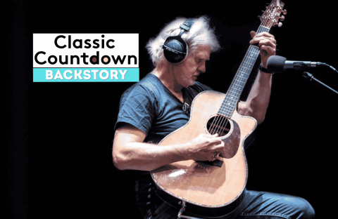 A man wearing headphones plays an acoustic guitar in a recording studio. To his left, text reads Classic Countdown Backstory on a dark background, setting the stage for a Backstory special featuring Robert Palmer&rsquo;s musical journey.