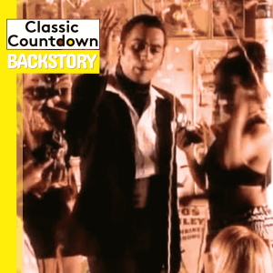 A person in a black and white outfit stands between two people dancing in a festive, indoor setting. The image includes the text Classic Countdown BACKSTORY on a yellow background, evoking the iconic style of Robert Palmer.