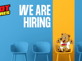Blue chairs against a blue and yellow wall set the scene, with “We Are Hiring” written in large white text. A cartoon bear wearing a Hot Cares shirt sits on a yellow chair, inviting applicants to join our caring team. The Hot Cares logo appears in the top left corner as we continue our mission to support important causes like Shona breast cancer awareness.