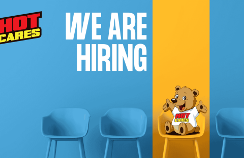 Blue chairs against a blue and yellow wall set the scene, with &ldquo;We Are Hiring&rdquo; written in large white text. A cartoon bear wearing a Hot Cares shirt sits on a yellow chair, inviting applicants to join our caring team. The Hot Cares logo appears in the top left corner as we continue our mission to support important causes like Shona breast cancer awareness.