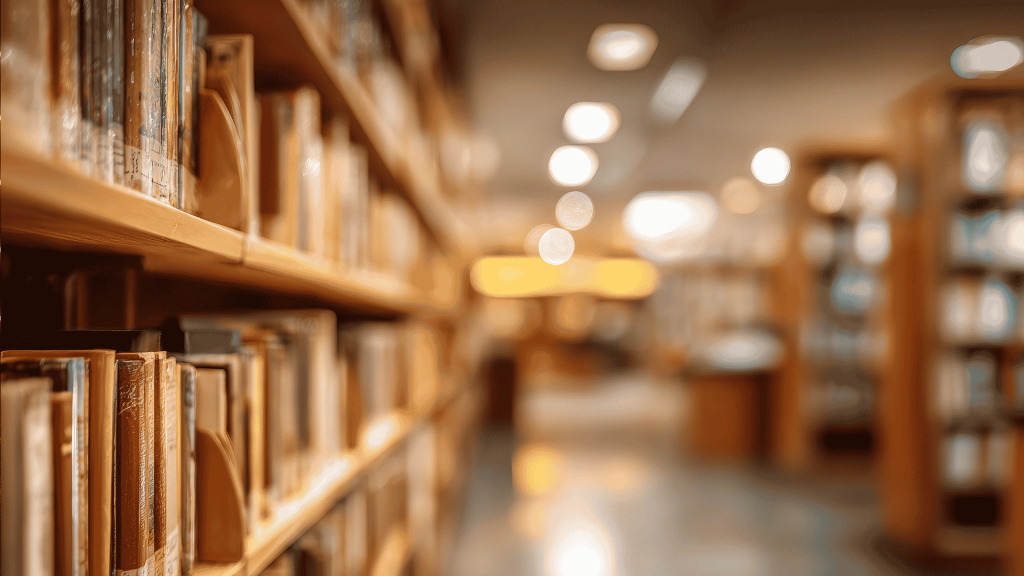 Rows of books on library shelves in soft focus, with warm lighting and a blurred background creating a calm, inviting atmosphere—like a bank of knowledge waiting to be explored.