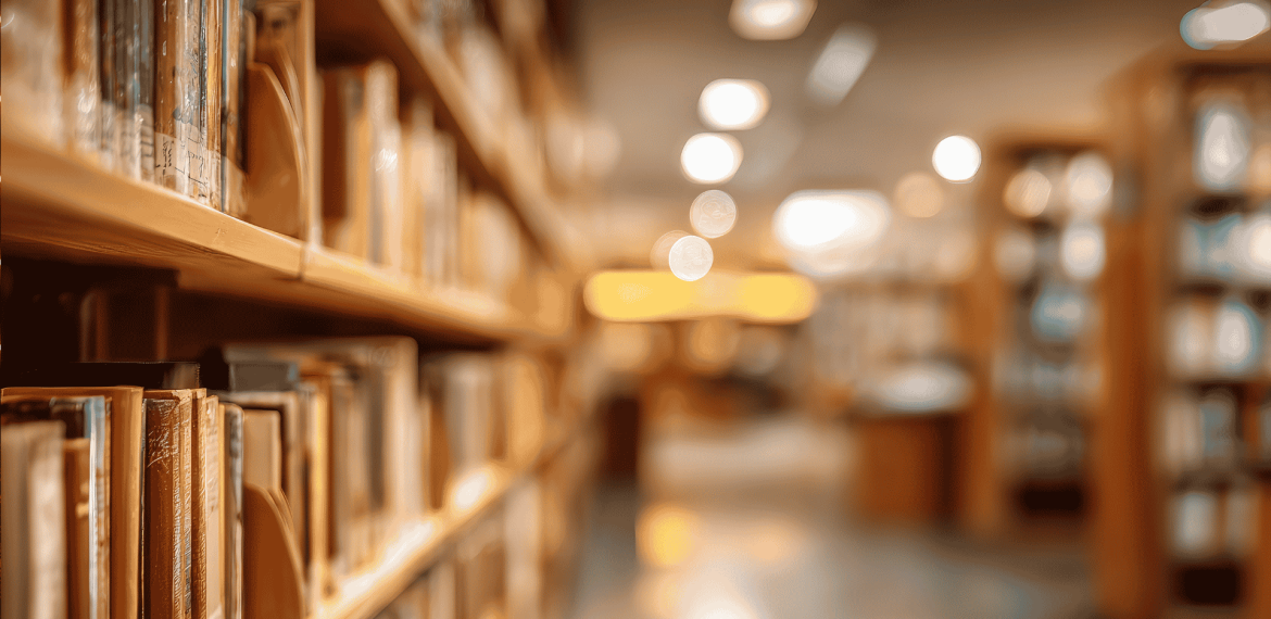 Rows of books on library shelves in soft focus, with warm lighting and a blurred background creating a calm, inviting atmosphere&mdash;like a bank of knowledge waiting to be explored.