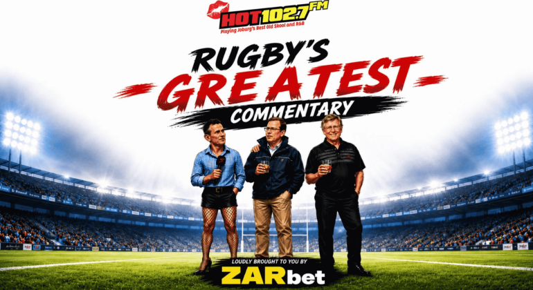 Three men stand on a rugby field holding drinks, wrapped warmly in winter blankets, with a stadium in the background. Text above them reads, Rugby’s Greatest Commentary, with HOT102.7FM and ZARbet logos also visible.
