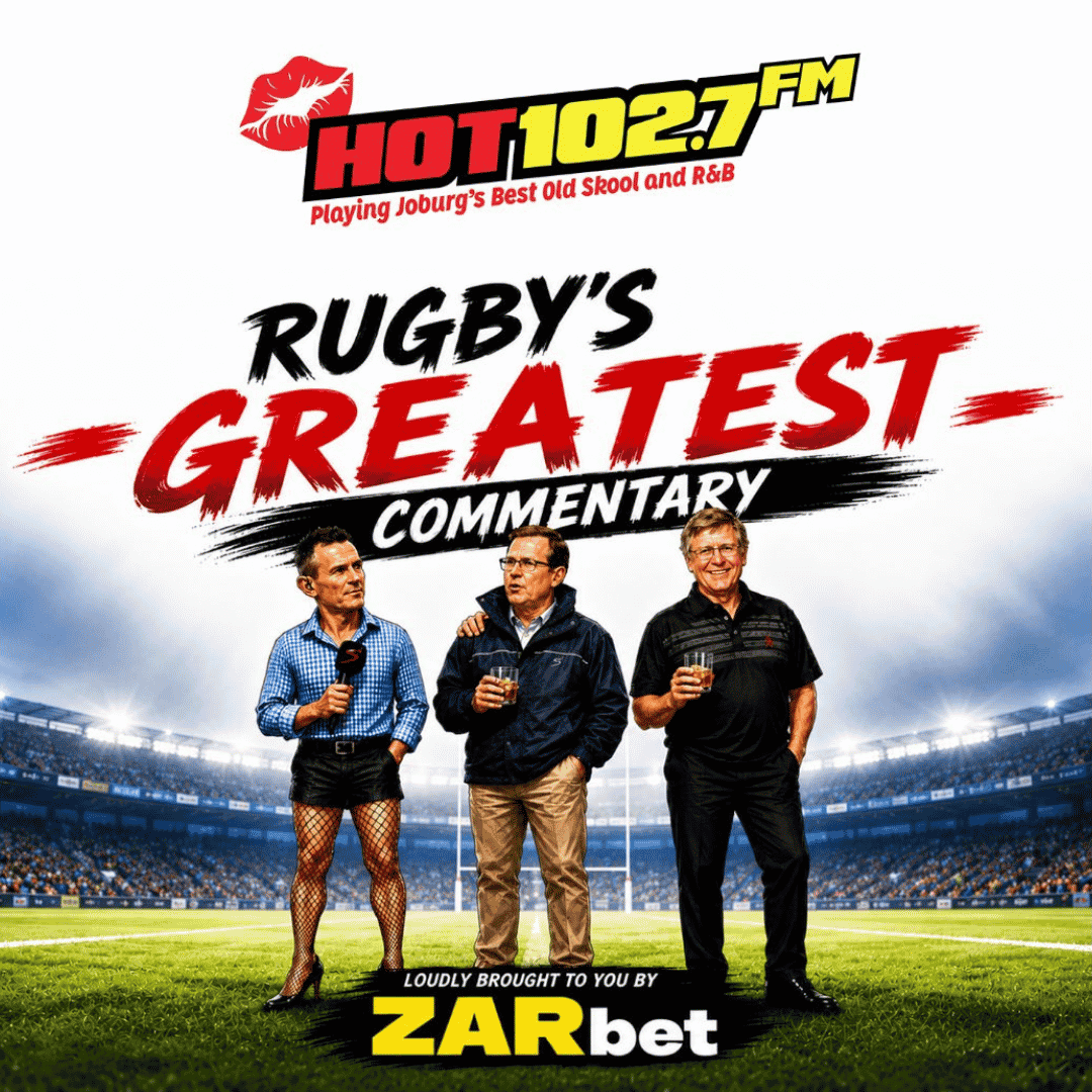 Three men stand on a rugby field holding drinks. One man wears a suit jacket, shorts, fishnet stockings, and drapes a winter blanket over his shoulders for extra flair. The text reads, Rugby’s Greatest Commentary and advertises HOT 102.7 FM and ZARbet.