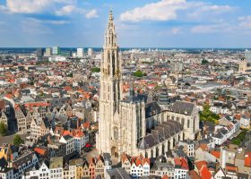 Aerial view of the Cathedral of Our Lady rising above the dense historic buildings and rooftops of Antwerp, Belgium.